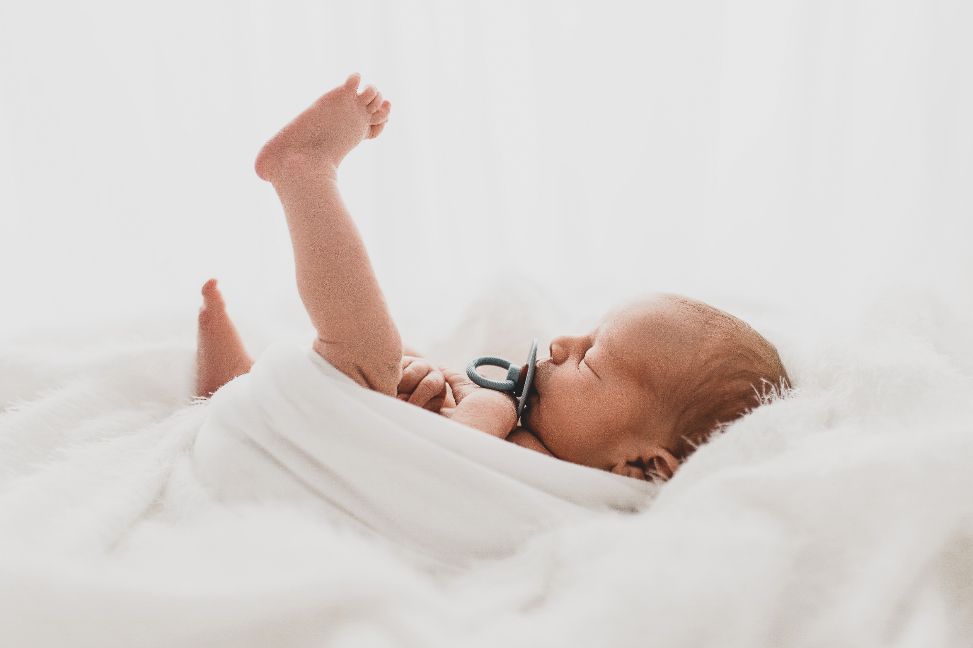 A swaddled newborn sleeping peacefully on a soft white blanket